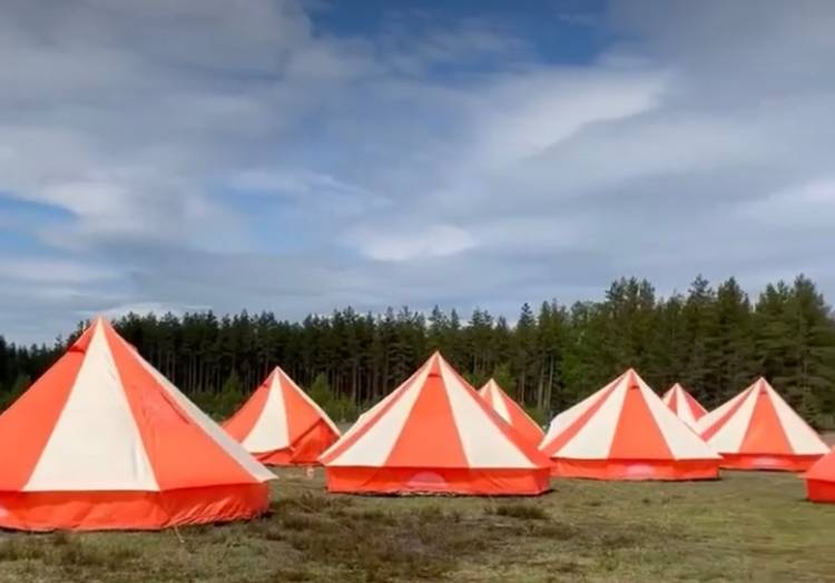 Sirkustelttoja, eli punavalkoisia isoja majoitustelttoja vihreällä nurmella.