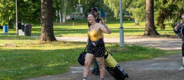 Festarikävijä saapuu tavaroineen iloisena leirintään.