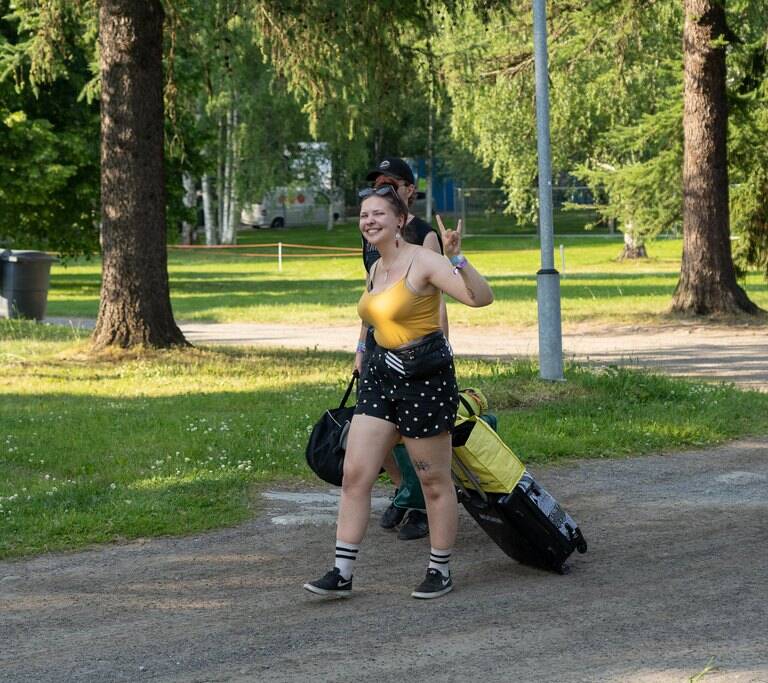 Festarikävijä saapuu tavaroineen iloisena leirintään.