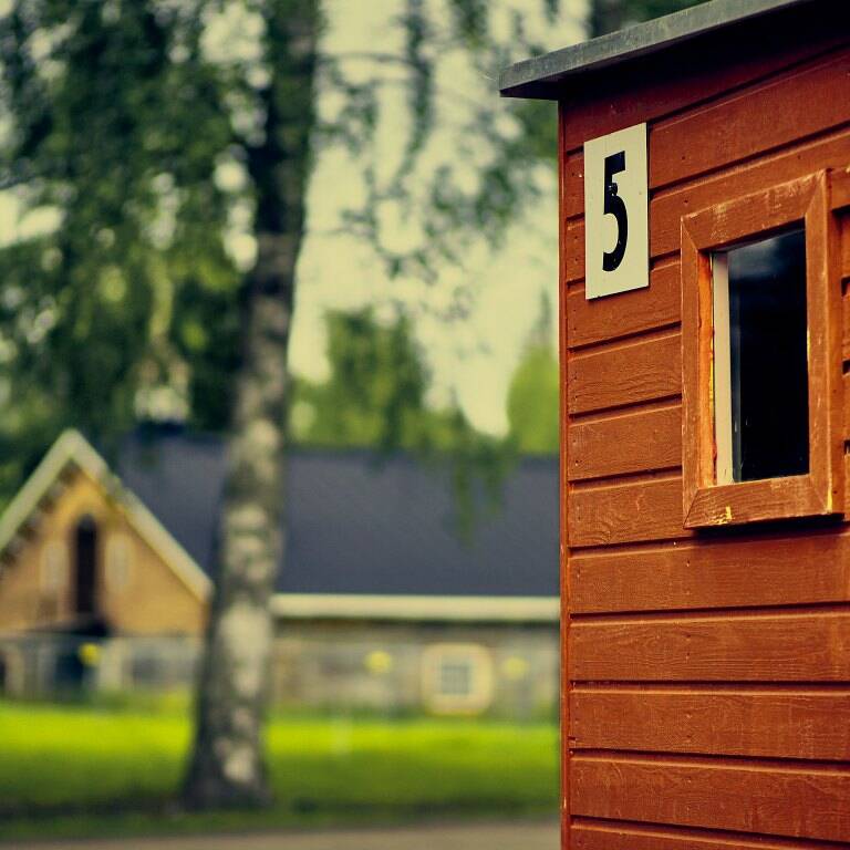 Vehreä puistoalue ja punaisen mökin kulma