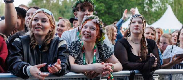 Festivaalivieraita nojaamassa eturivissä aitaan.