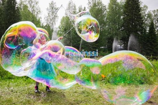 Isoja värikkäitä saippuakuplisa Provinssin alueohjelman esiintyjän tekeminä. Taustalla joki ja Provinssi-kirjaimet joessa.