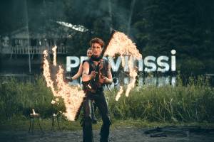 Flamman tulishow joen rannassa Provinssi-kyltin edessä. Miesoletetulla on kädessään keppi, jonka molemmissa päissä on isot tulilieskat.